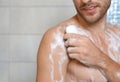 Young man taking shower with soap in bathroom Royalty Free Stock Photo