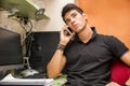 Young Man Talking on Cell Phone at Computer Desk Royalty Free Stock Photo