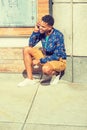 Young man talking on cell phone,  squatting by coloumn on street in New York City Royalty Free Stock Photo