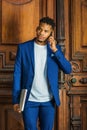 Young man talking on cell phone, standing by office door in New York City