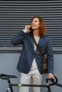 Young man talking on cellphone while standing with bicycle near grey wall Royalty Free Stock Photo