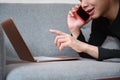 Man talking on mobile phone while lying on sofa with laptop computer. Royalty Free Stock Photo