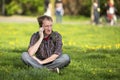 Young man talking on mobile phone sitting on the green grass Royalty Free Stock Photo