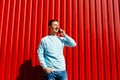 Young man talking on mobile phone and standing on the background of red wall Royalty Free Stock Photo