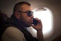 Young man talking on phone in airplane. Close up image. Royalty Free Stock Photo