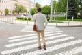 Young man talking on phone while crossing street, back view. Traffic rules and regulations Royalty Free Stock Photo