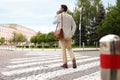 Young man talking on phone while crossing street, back view. Traffic rules Royalty Free Stock Photo