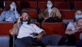 Young man talking on phone in movie theater. Media. Impudent man is talking on phone in movie theater and interferes Royalty Free Stock Photo