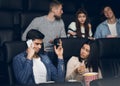 Young man talking on smartphone during film premiere in movie theater