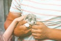 a young man with tanned arms is holding a very small puppy. the baby is petting him. daylight. close-up