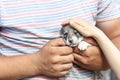 a young man with tanned arms is holding a very small puppy. the baby is petting him. daylight. close-up