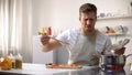 Young man tasting cooked food with disgusted face expression, funny grimacing