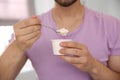 Young man with tasty yogurt on background, closeup