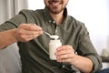 Young man with tasty yogurt indoors