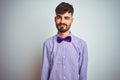 Young man with tattoo wearing purple shirt and bow tie over isolated white background winking looking at the camera with sexy Royalty Free Stock Photo