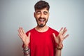 Young man with tattoo wearing red t-shirt standing over isolated white background celebrating mad and crazy for success with arms Royalty Free Stock Photo