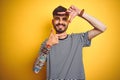 Young man with tattoo wearing striped t-shirt standing over isolated yellow background smiling making frame with hands and fingers Royalty Free Stock Photo