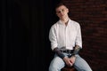 Young man with tattoos sitting on stool indoors. Space for text Royalty Free Stock Photo