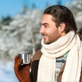 Young man with tea standing in snowy woods Royalty Free Stock Photo