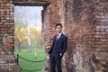 A young man, a teenager, in a classic suit. Foolishly stands opposite the old wall of red brick, putting his hands in his pockets. Royalty Free Stock Photo