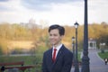 A young man, a teenager, in a classic suit. Walking along the avenues of the spring park.