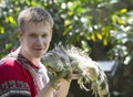 Young man, the teenager holds an iguana on hands Royalty Free Stock Photo