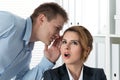 Young man telling gossips to his woman colleague