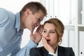 Young man telling gossips to his woman colleague