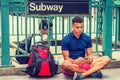 Young man texting on cell phone, sitting on ground by subway station in New York City Royalty Free Stock Photo