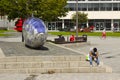 A young man texting sits beside the large fish sculpture on the Donegall Quay in the harbour area of Belfast, Northern Ireland