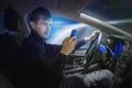 Young man is texting using smartphone and driving a car at night. Royalty Free Stock Photo