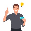 Young man thinking and got an idea for using a credit card. Pointing his finger up with light bulb of idea appears Royalty Free Stock Photo