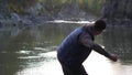 Young man throwing stones in the mountain river Royalty Free Stock Photo