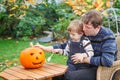 Young man and toddler boy making halloween pumpkin