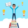 Young man on top of a mountain of books. Student celebrates getting new knowledge and ideas by reading. Royalty Free Stock Photo