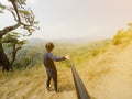 Young man on the top of mountain taking picture with camera on selfie stick