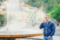 Young man tourist with blue jacket look at camera and drink therapeutic mineral water from cup