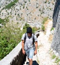 A young man tourist climbs up the stairs to the old ancient fortress. Ruins of St. John fortress in the Kotor Bay in Montenegro. Royalty Free Stock Photo