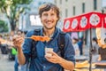 Young man tourist eating Typical Korean street food on a walking street of Seoul. Spicy fast food simply found at local