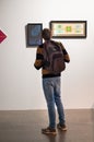 A young man, a tourist, examines works at an exhibition of contemporary art in the museum.