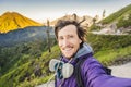 Young man tourist makes a selfie with the magnificent views on green mountains from a mountain road trecking to the Ijen Royalty Free Stock Photo