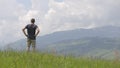 Young man tourist raising his hands in winner gestion while hiking in summer mountains.