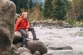 Young man tourist sits rocky mountain river bank