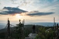 Young man tourist in white cap standing on rock at sunset in landscape, Sumava National Park and Bavarian Forest, Czech republic