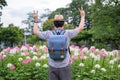 Young man tourists backpack are standing for victory performances hand sign. at spider flower garden. during traveling in the Royalty Free Stock Photo