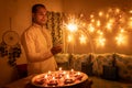 Young man in traditional dress holding the fireworks in hand with ferry lights background