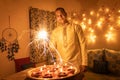 Young man in traditional dress holding the fireworks in hand with ferry lights background