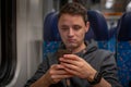 Young man on the train reads news on his smartphone Royalty Free Stock Photo