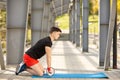 Young man training yoga outdoors. Sporty guy makes stretching exercise on a blue yoga mat, on the sports ground Royalty Free Stock Photo