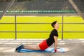 Young man training yoga outdoors. Sporty guy makes stretching exercise on a blue yoga mat, on the sports ground Royalty Free Stock Photo